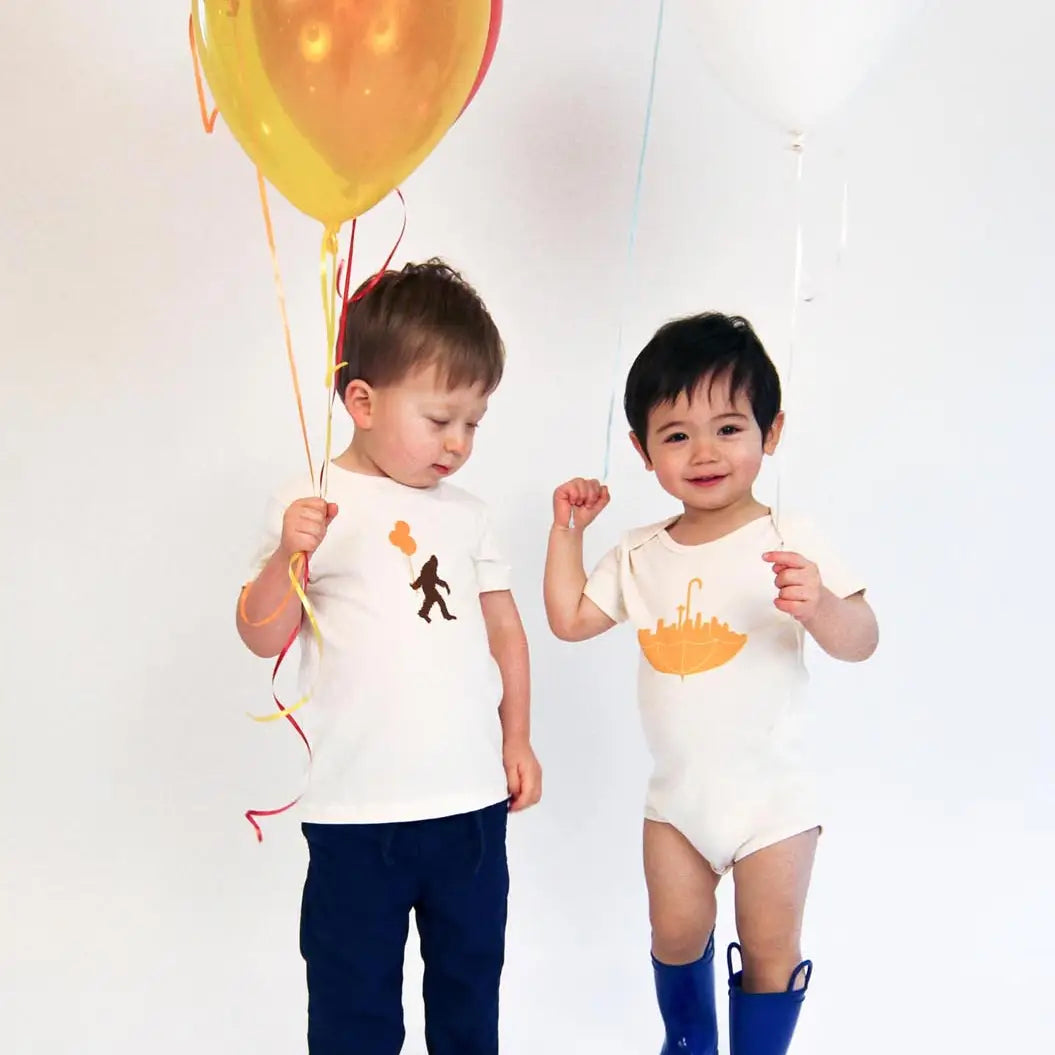 two children standing holding balloons wearing Sasquatch and balloons and Seattle umbrella tee