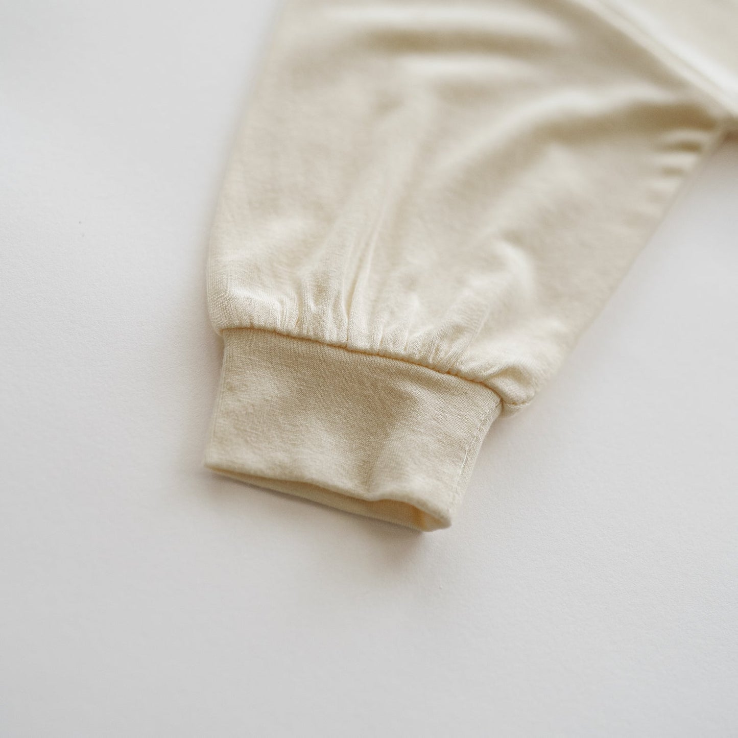Close-up of a beige sweatshirt sleeve on a light gray background