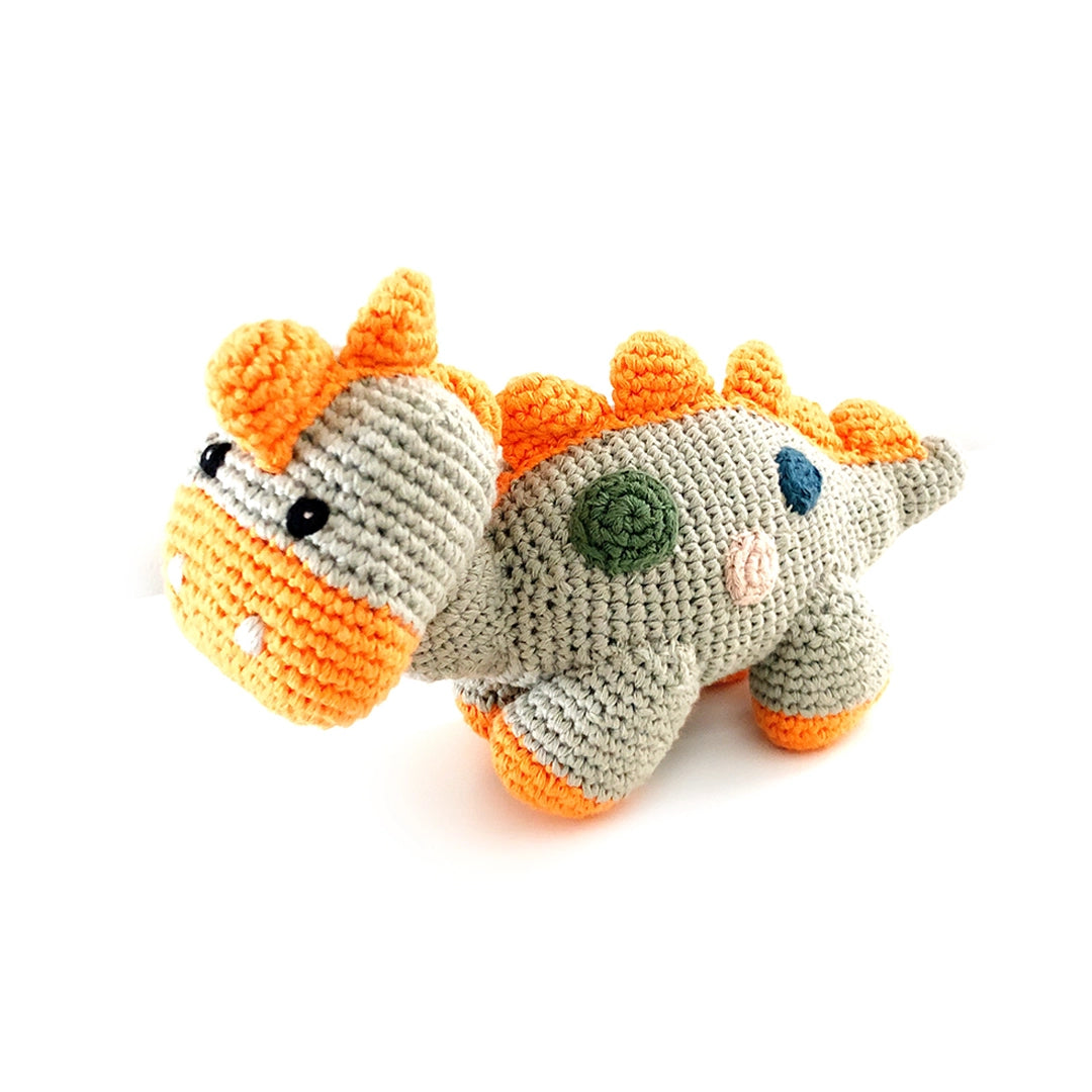 Crochet dinosaur toy with orange spikes on a white background