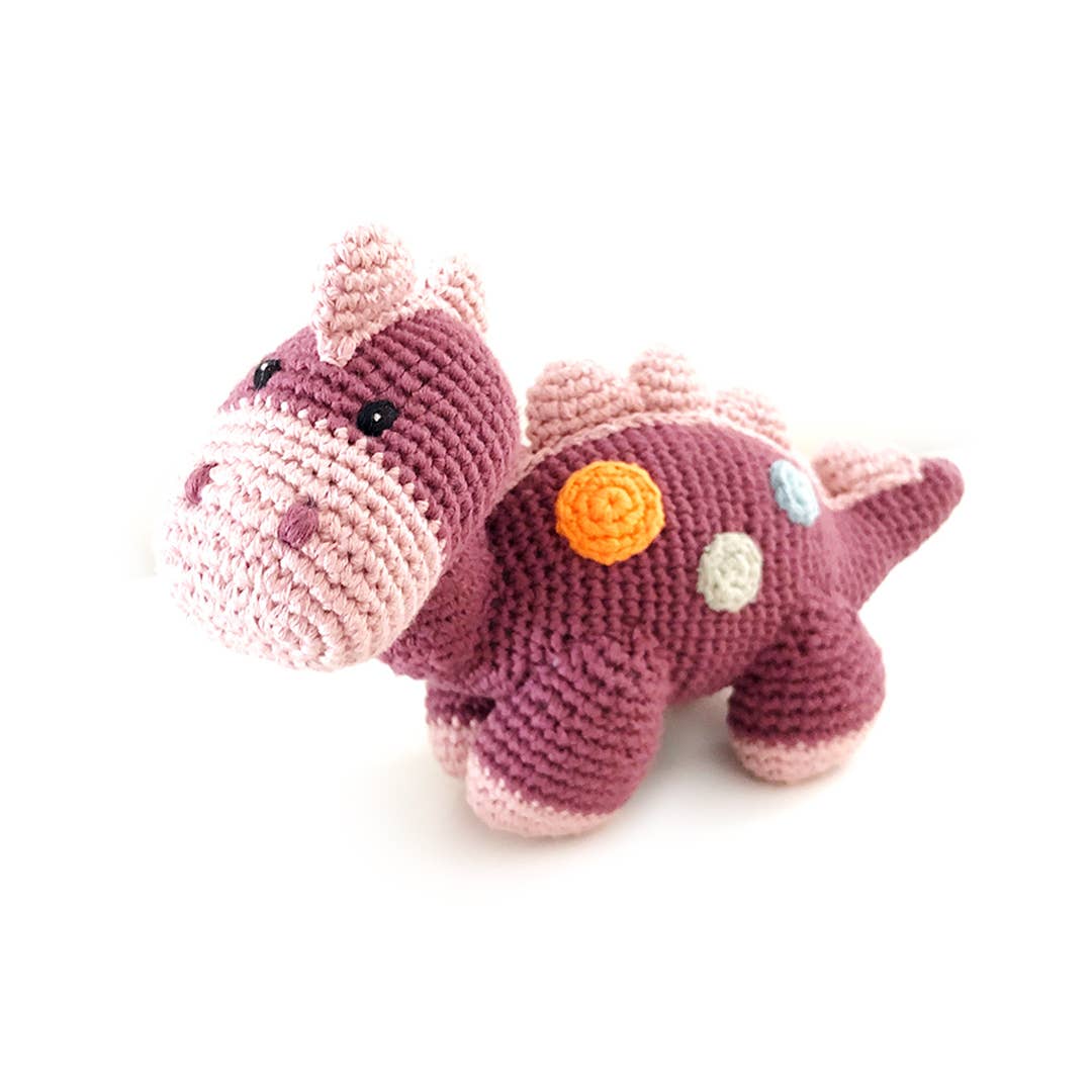 Crocheted dinosaur toy with pink and purple colors on a white background