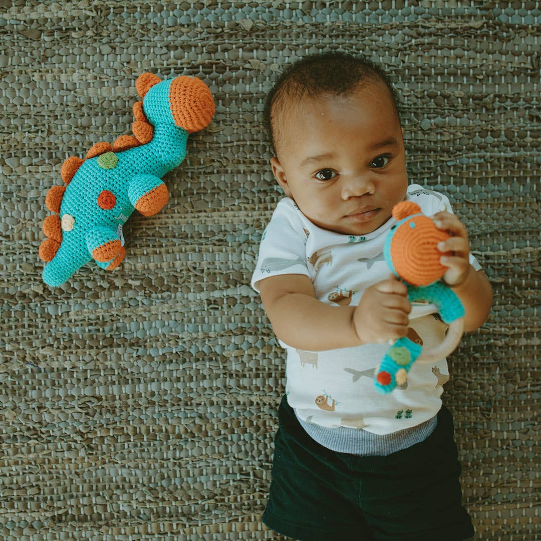 Baby holding a toy dinosaur against a textured wall