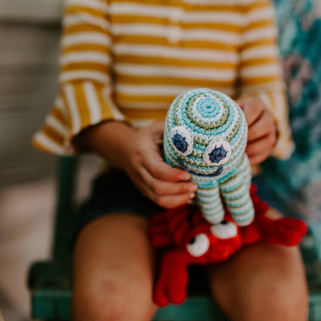 Person holding a colorful crochet octopus toy with a blurred background