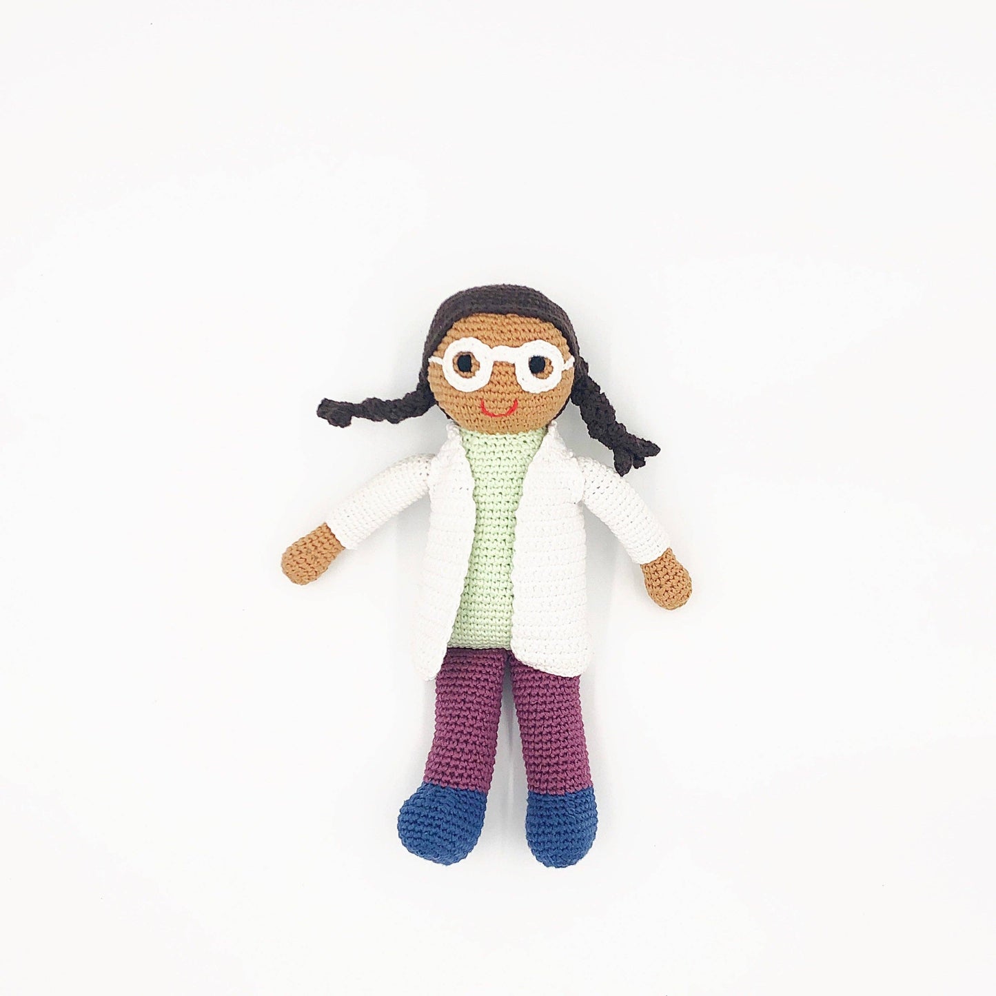 Crocheted doll of a person wearing a white lab coat, glasses, and purple pants on a white background