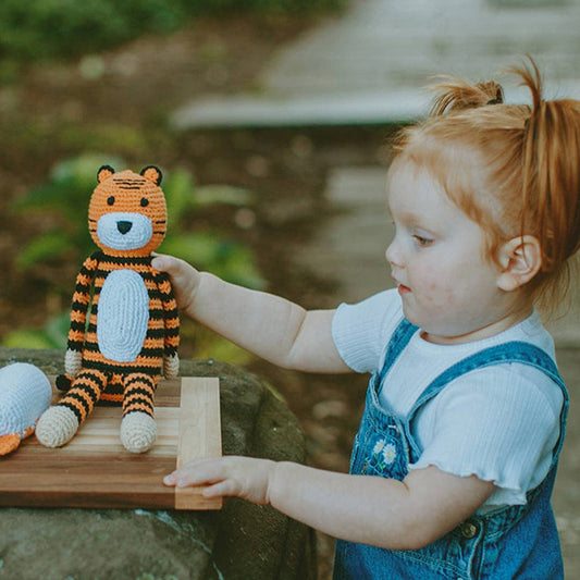Child playing with a toy tiger outdoors