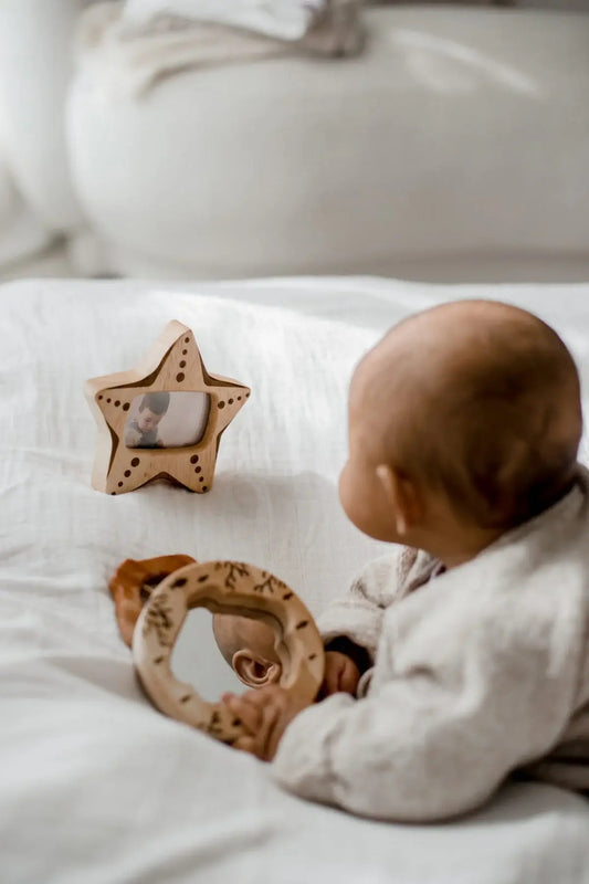 a baby laying on their stomach on a bed playing with a wooden ocean gift set