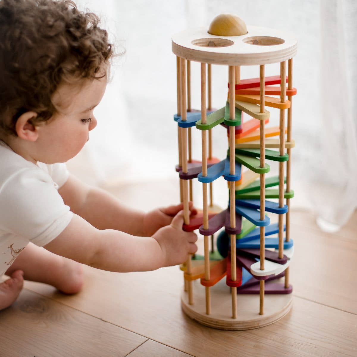 a baby sitting on the floor playing with pound-a-ball tower