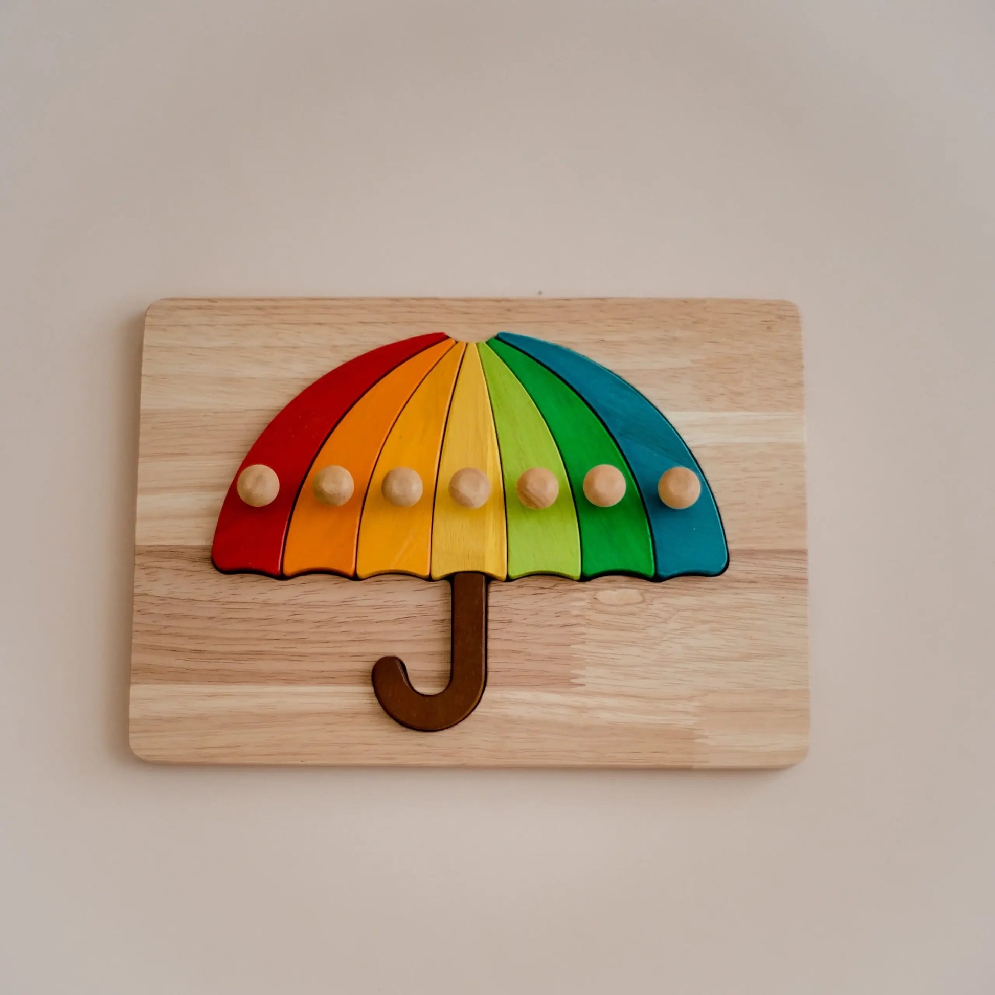 Wooden puzzle shaped like a rainbow umbrella on a beige background