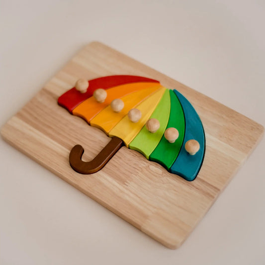Wooden rainbow umbrella puzzle on a wooden base with a plain background
