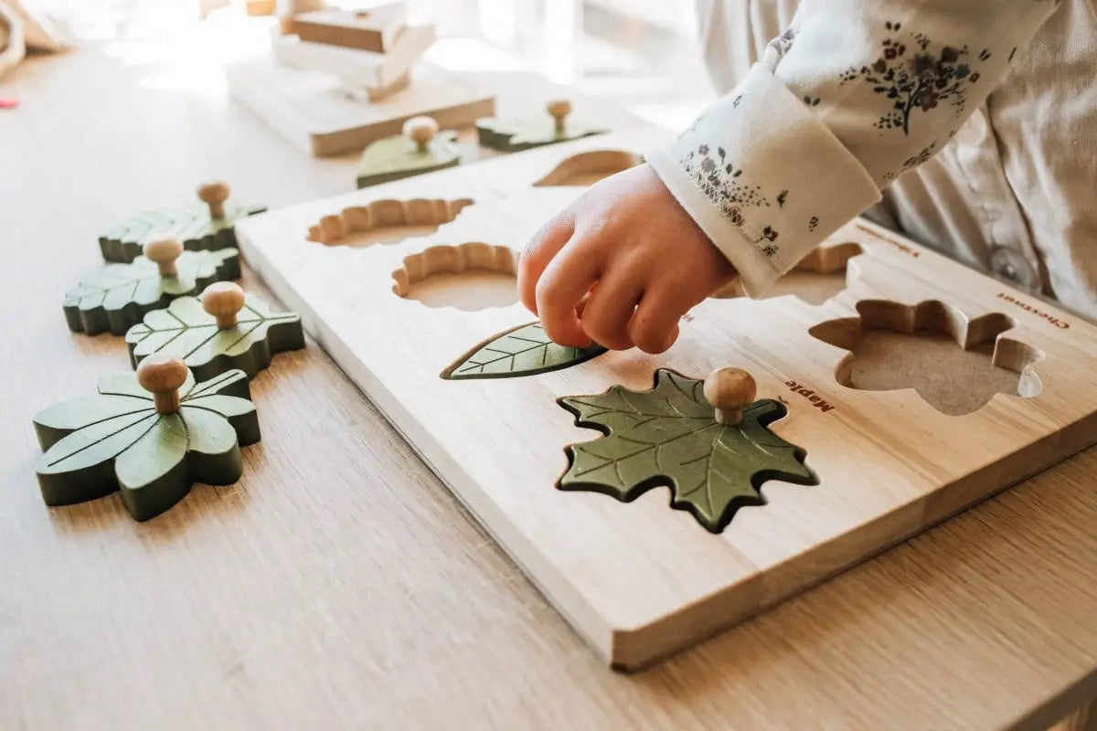 Child playing with Montessori leaf puzzle on a wooden table