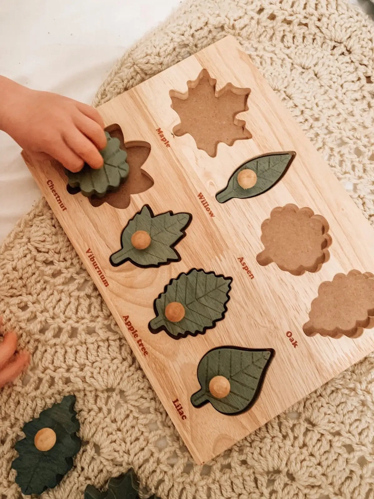 Child playing with Montessori leaf puzzle on a rug