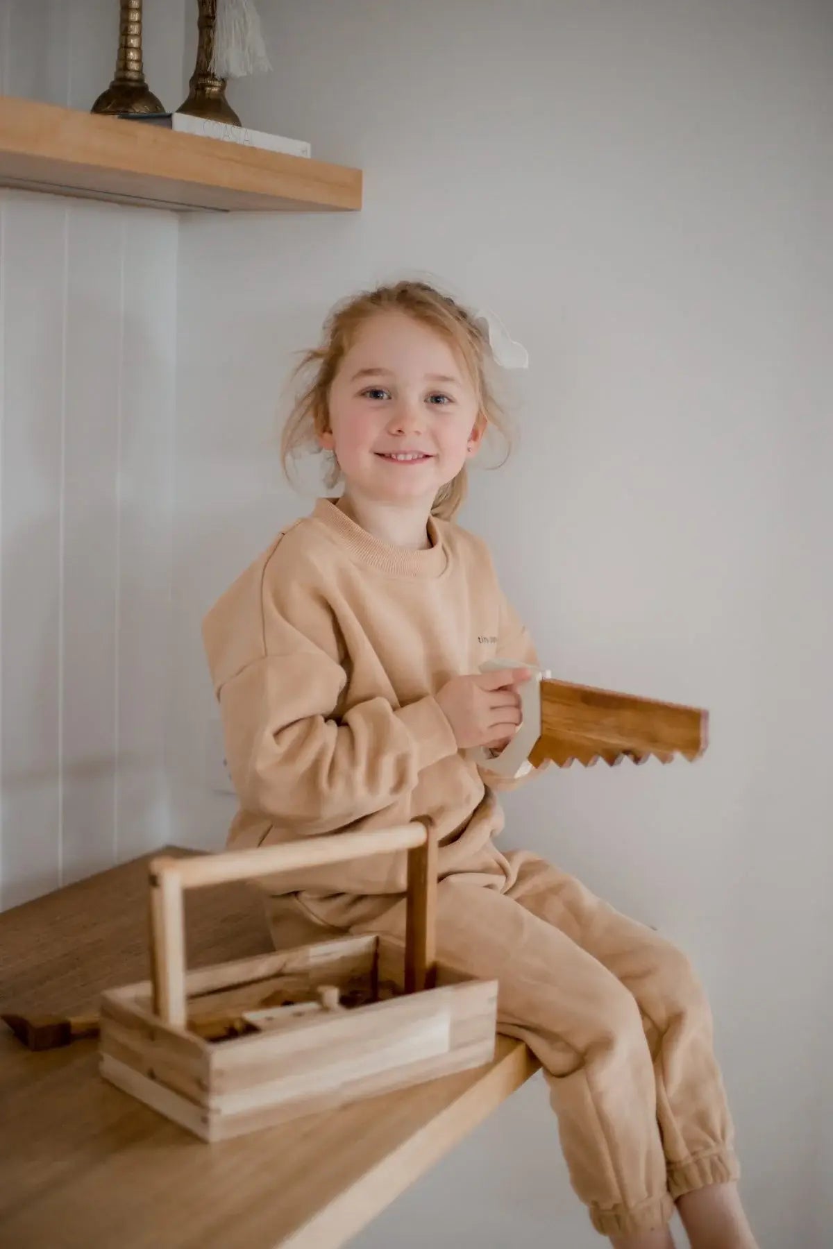 child playing with wooden tool set on a bench