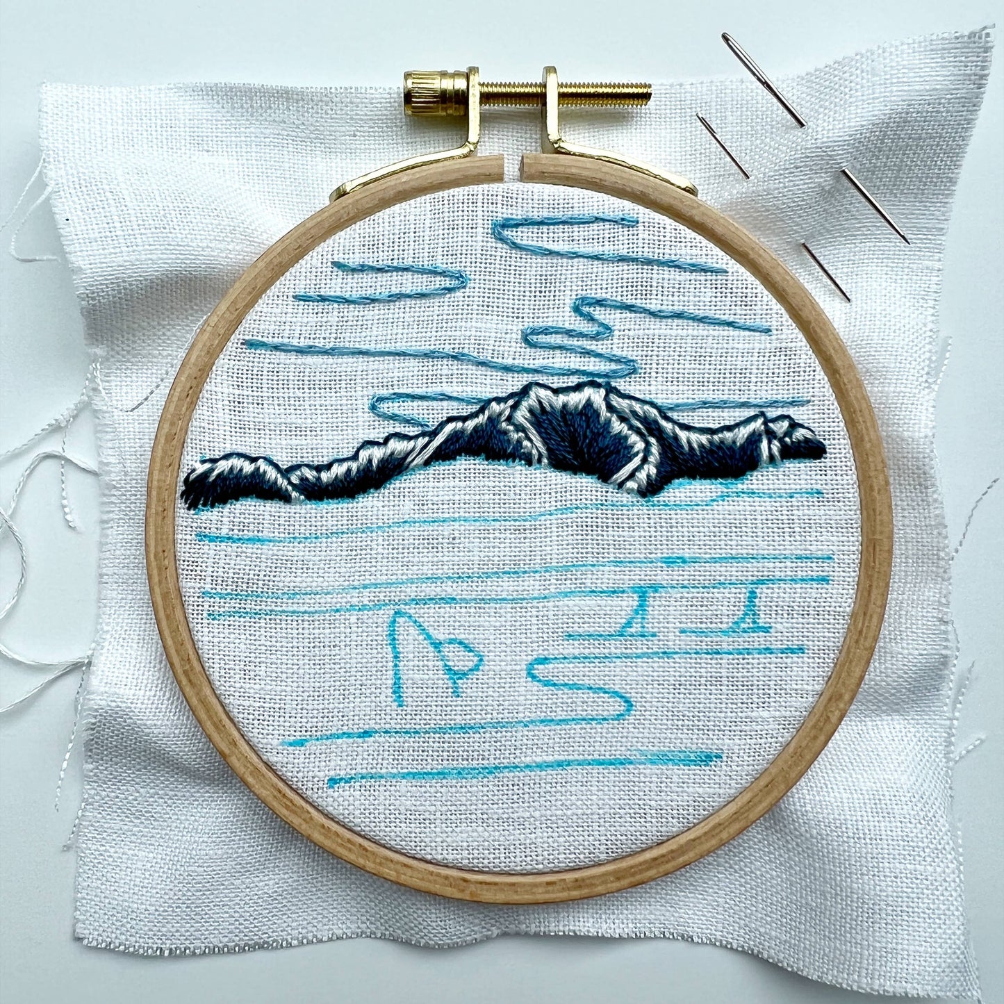 Embroidery hoop with a mountain design and traced pattern on white fabric
