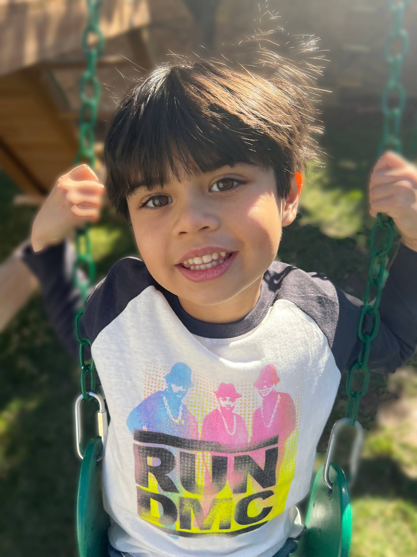 a toddler on a swing wearing recycled Run DMC raglan tee