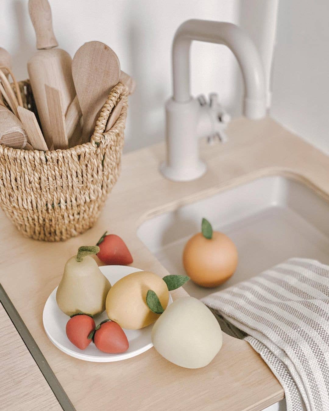 a mini wooden fruit set on a play kitchen sink