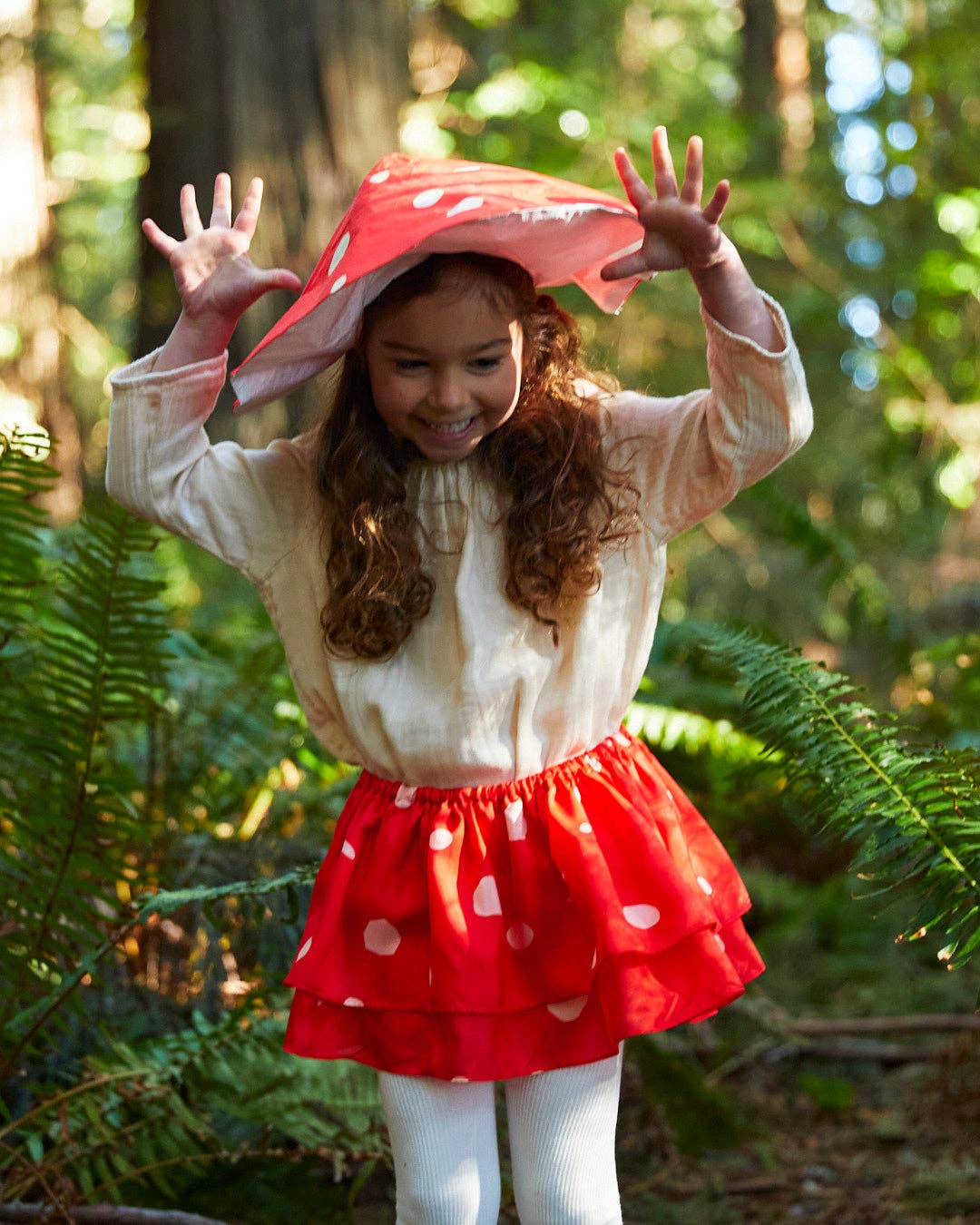 Child standing in the woods wearing a silk mushroom outfit