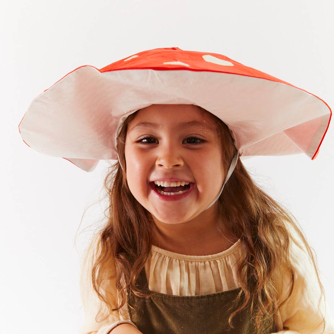 Child laughing wearing a mushroom hat