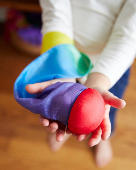 Close-up of a child's hands holding a rainbow silk skytail