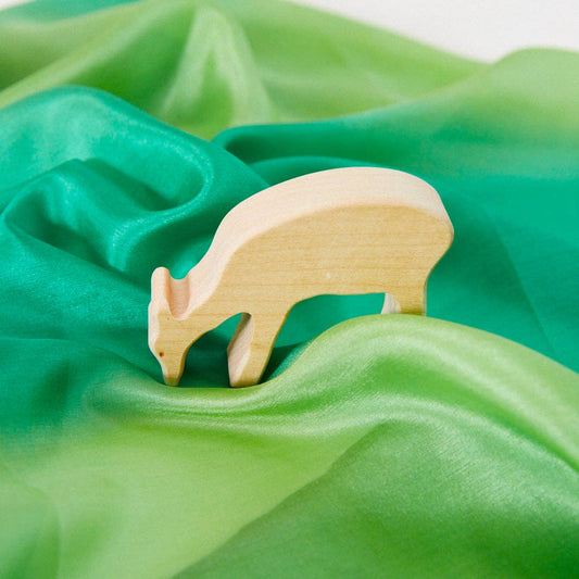 Wooden deer figurine standing on a forest playsilk