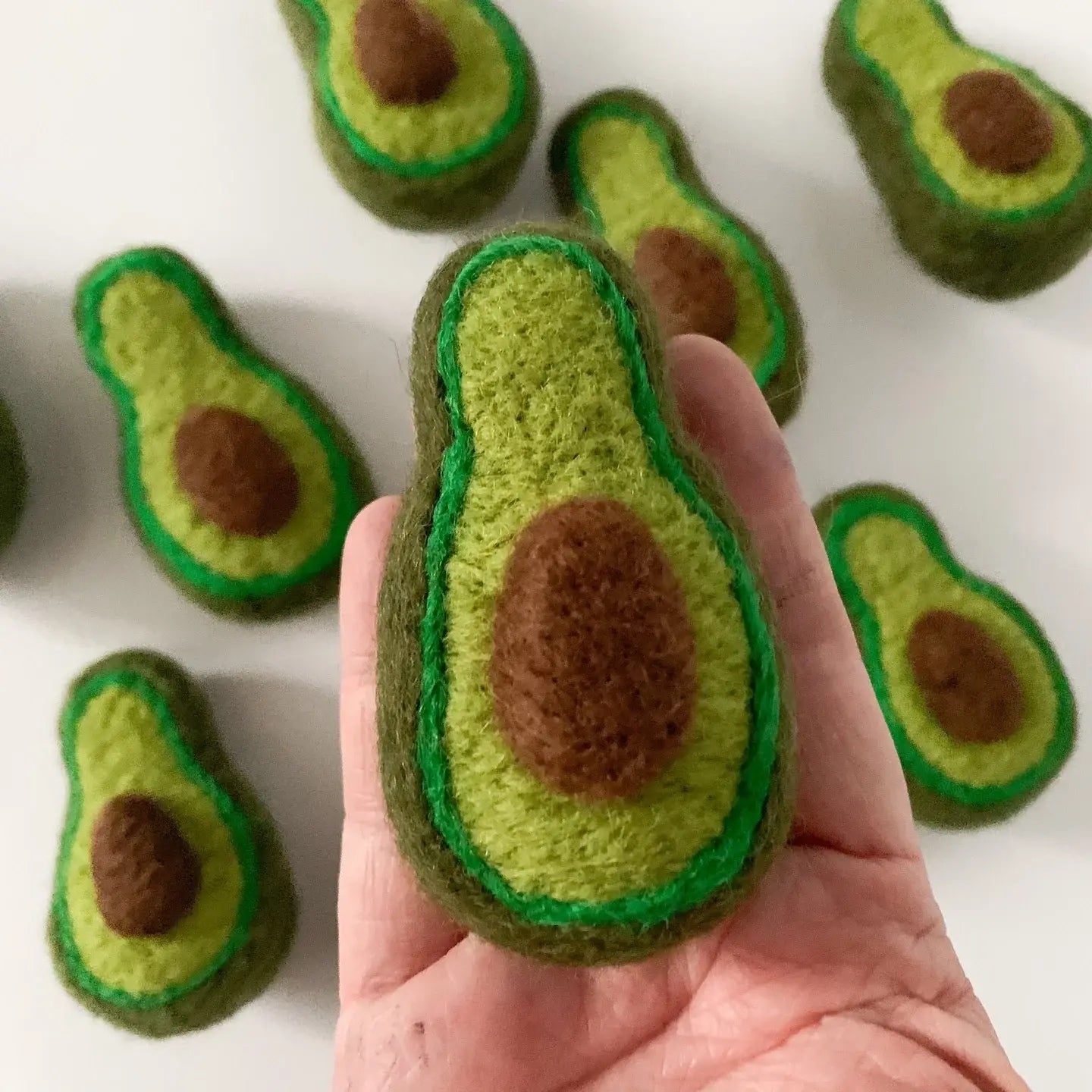 a hand holding a felt avocado