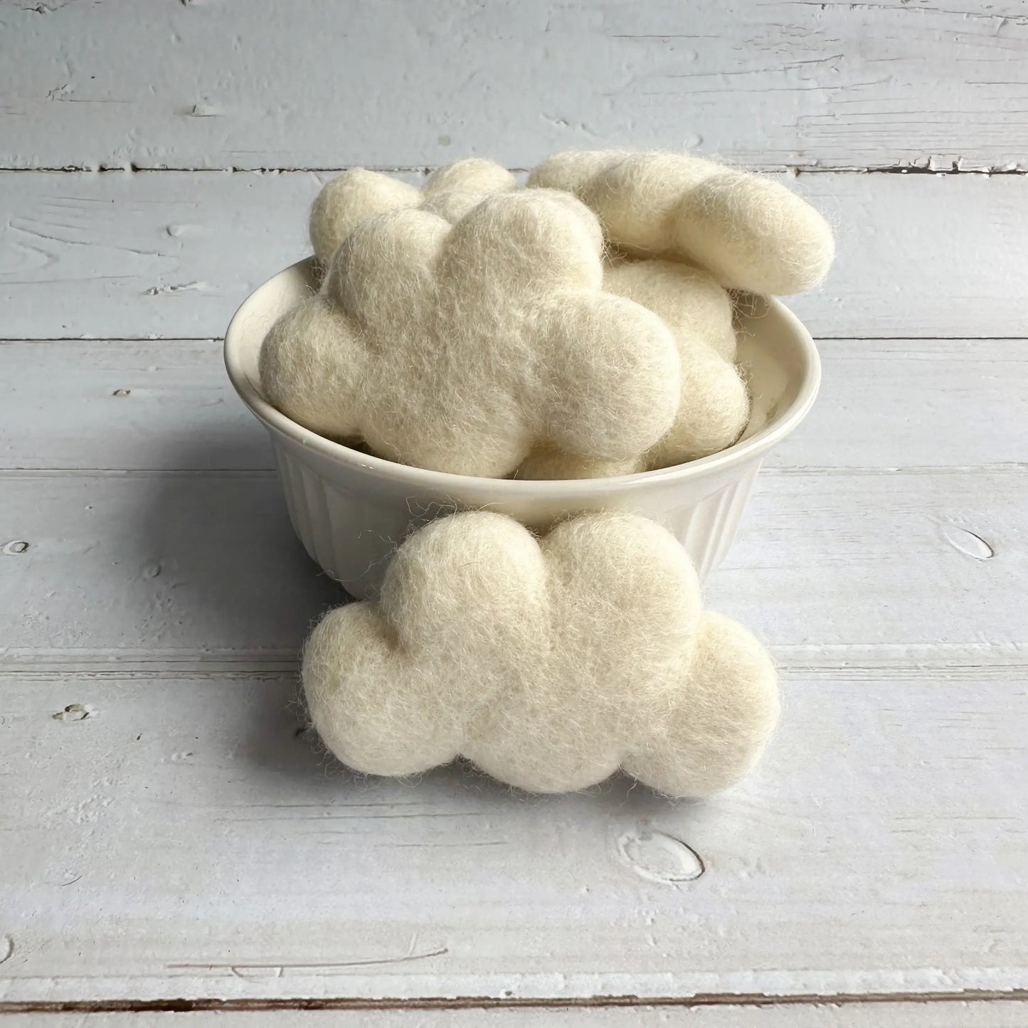 a ceramic bowl filled with felt white clouds