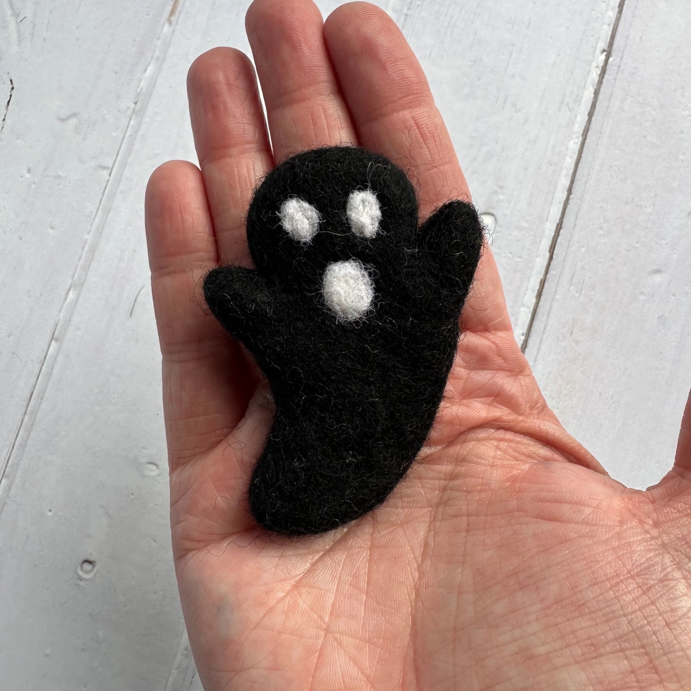 hand holding a black felt ghost