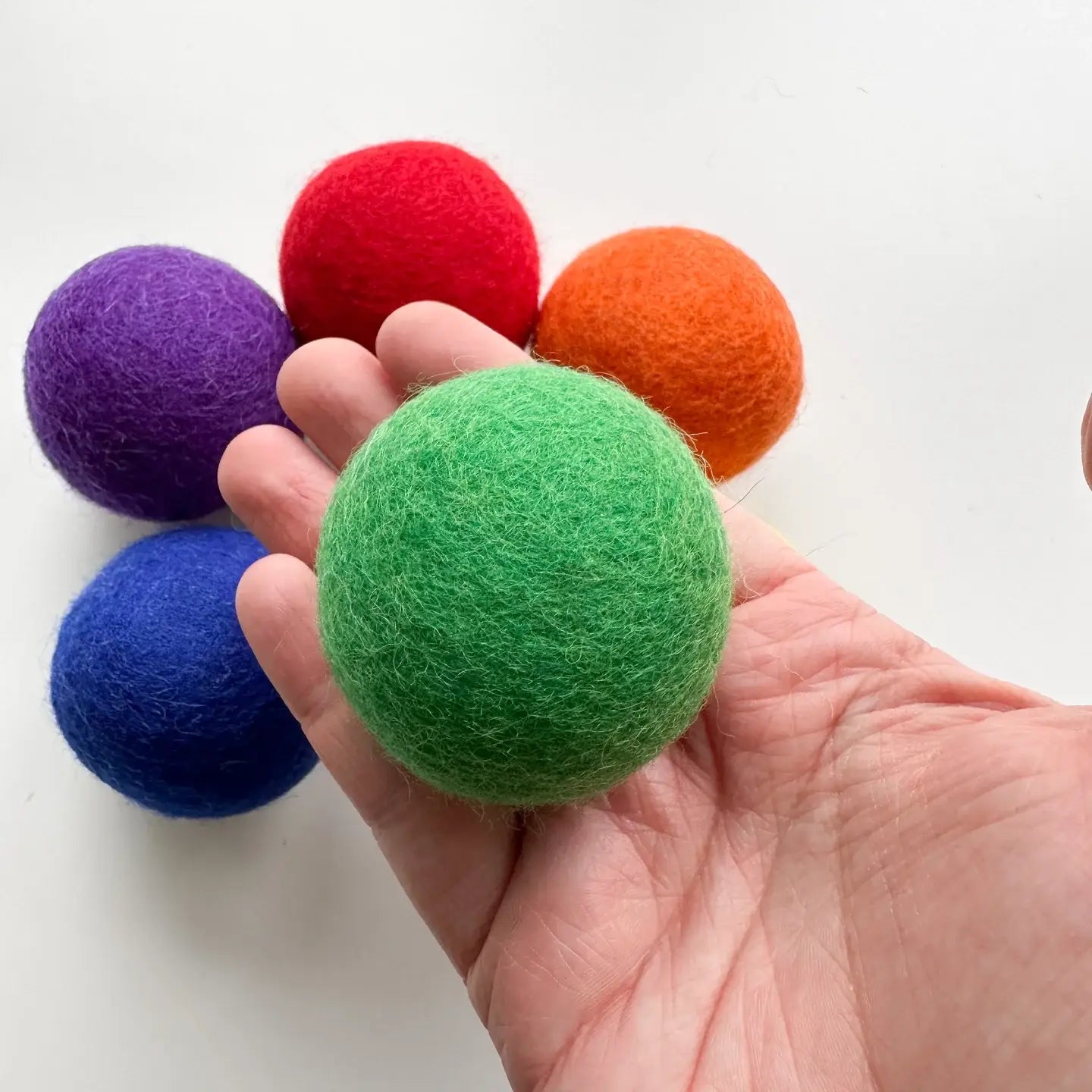 a hadn holding a felt green ball