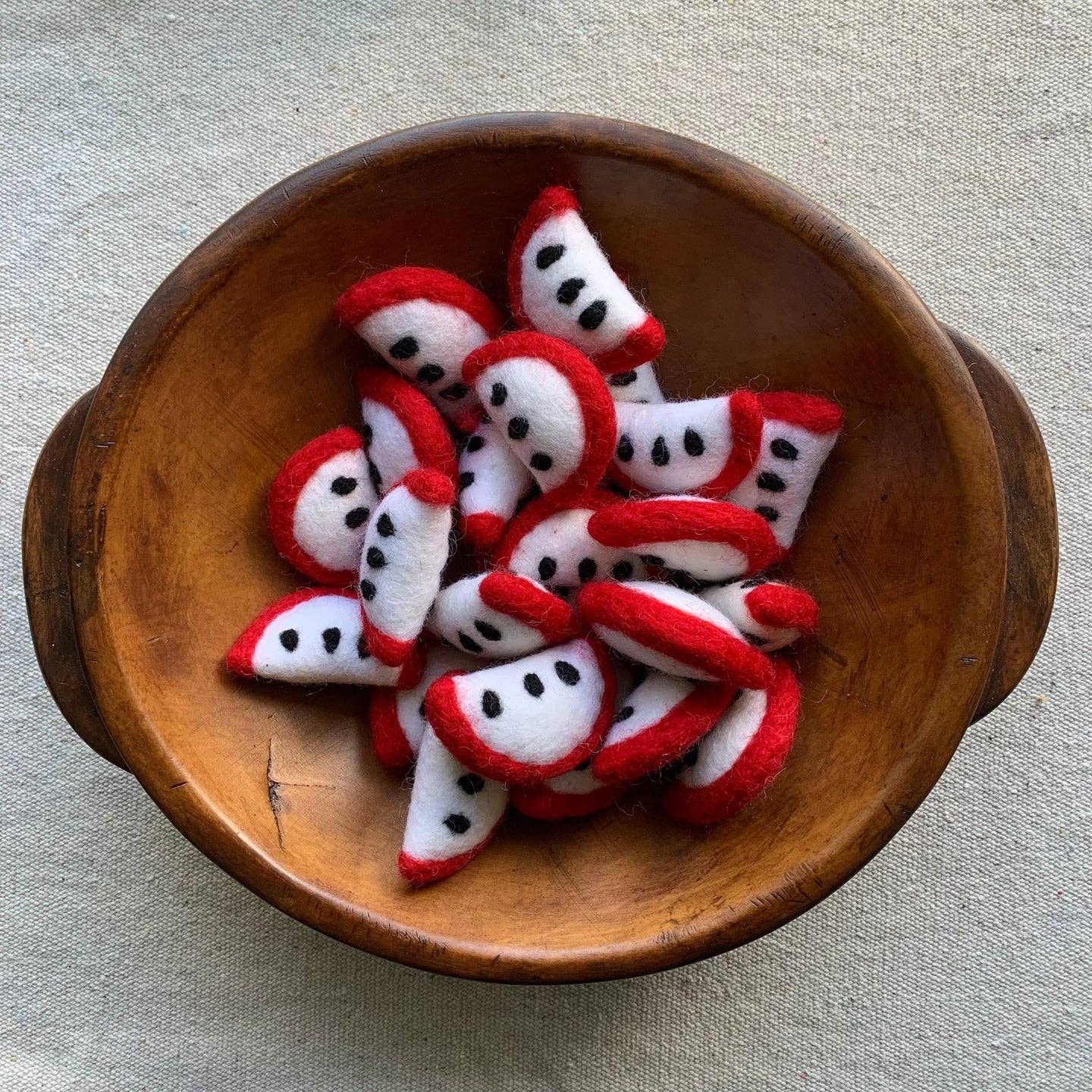 a wooden bowl filled with felt red apple slices