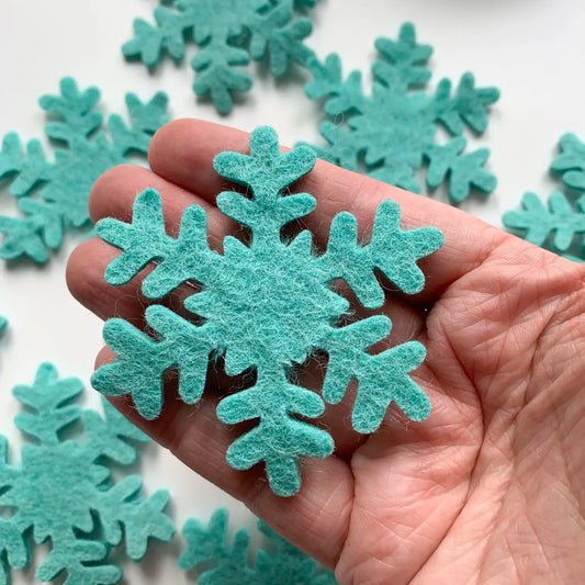 hand holding a blue felt snowflake cutout