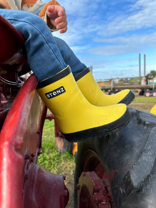 Child wearing yellow Stonz boots on a tractor