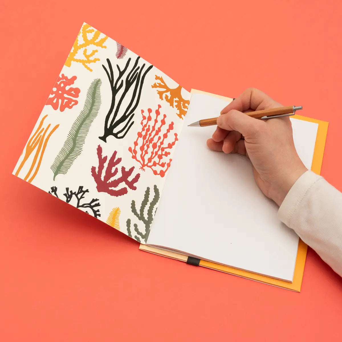 person writing in seaweed notebook