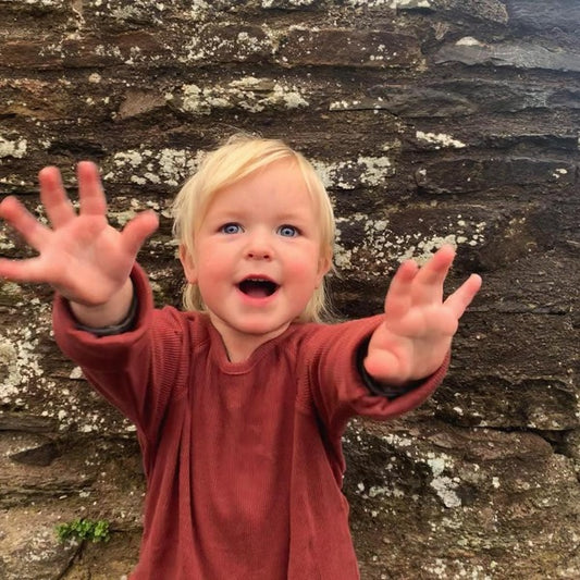 child reaching their hands towards the camera wearing organic ribbed brick raglan