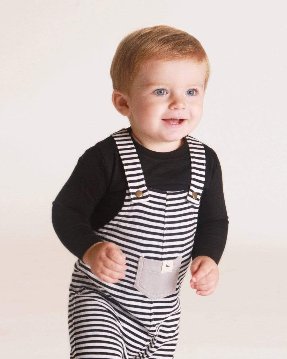 Baby wearing striped humbug overalls over a black long sleeve tee