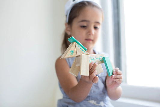 a child sitting by a window wearing a matching lavender dress and hairband set playing with a magnetic Robo horse by Tegu