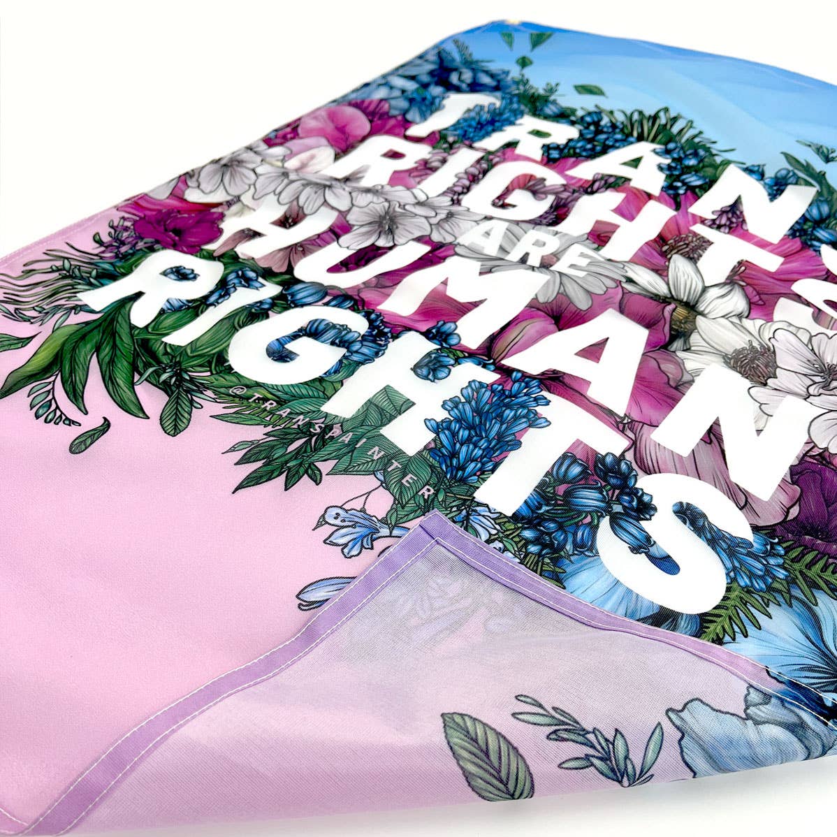 trans pride flag with a flower print decoration and the words "trans rights are human rights" printed on it