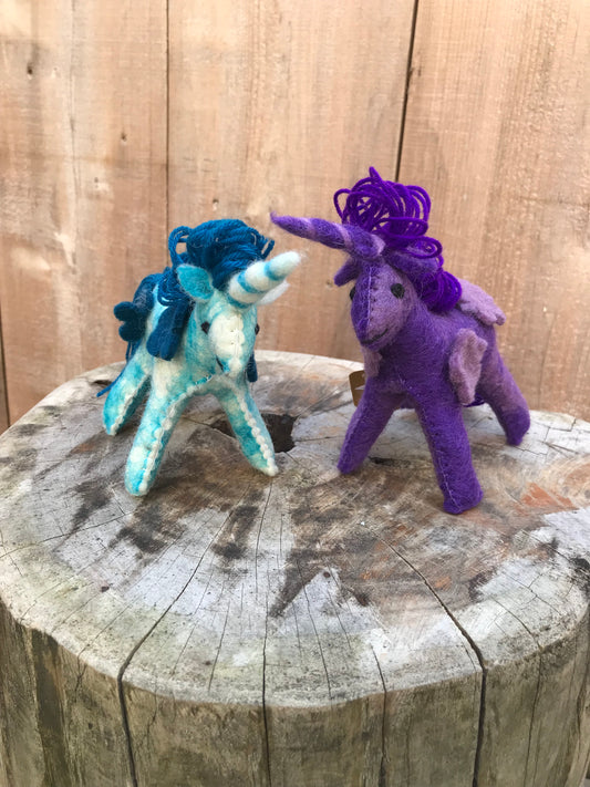 Small wool felt unicorn on a wooden trunk