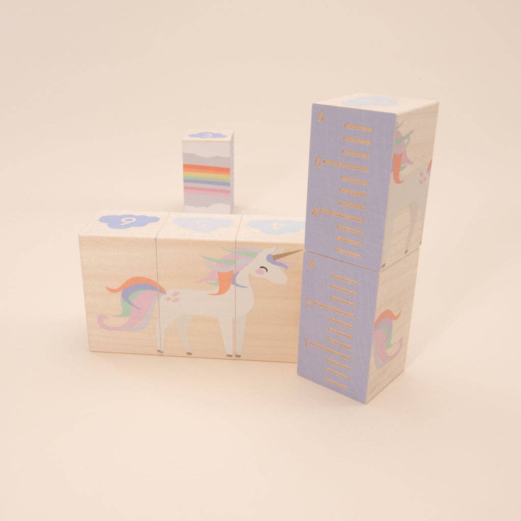 Unicorn-themed wooden blocks with a measuring stick on a beige background