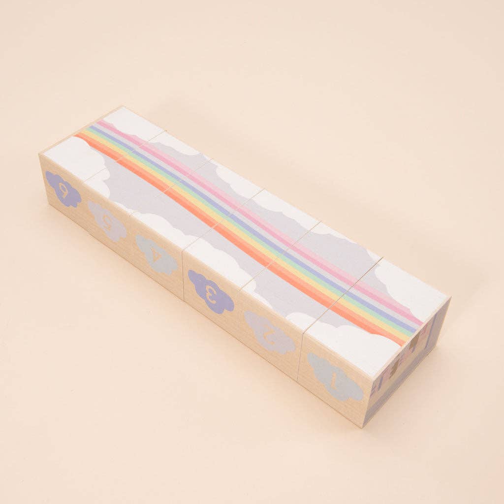 Wooden blocks with a rainbow and clouds design on a beige background