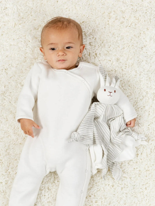 baby laying on a sherpa blanket holding a striped bunny lovey