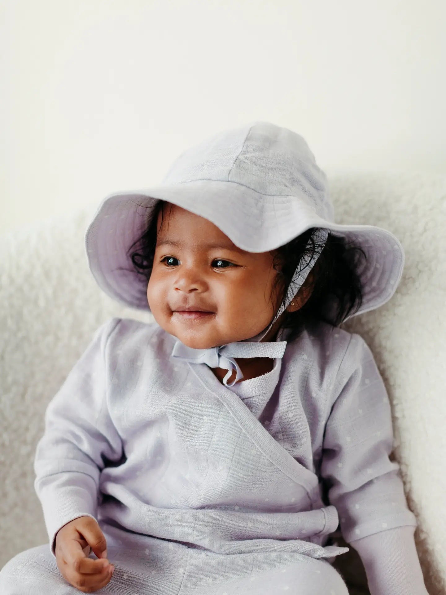 baby wearing lavender stars muslin sun hat and matching romper