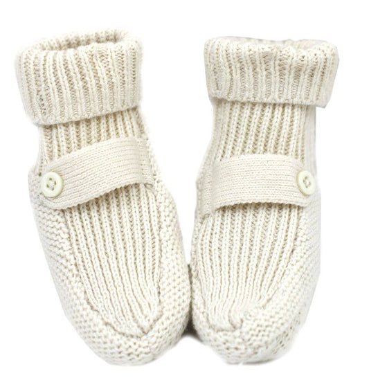 Pair of cream knitted baby booties with button details on a white background