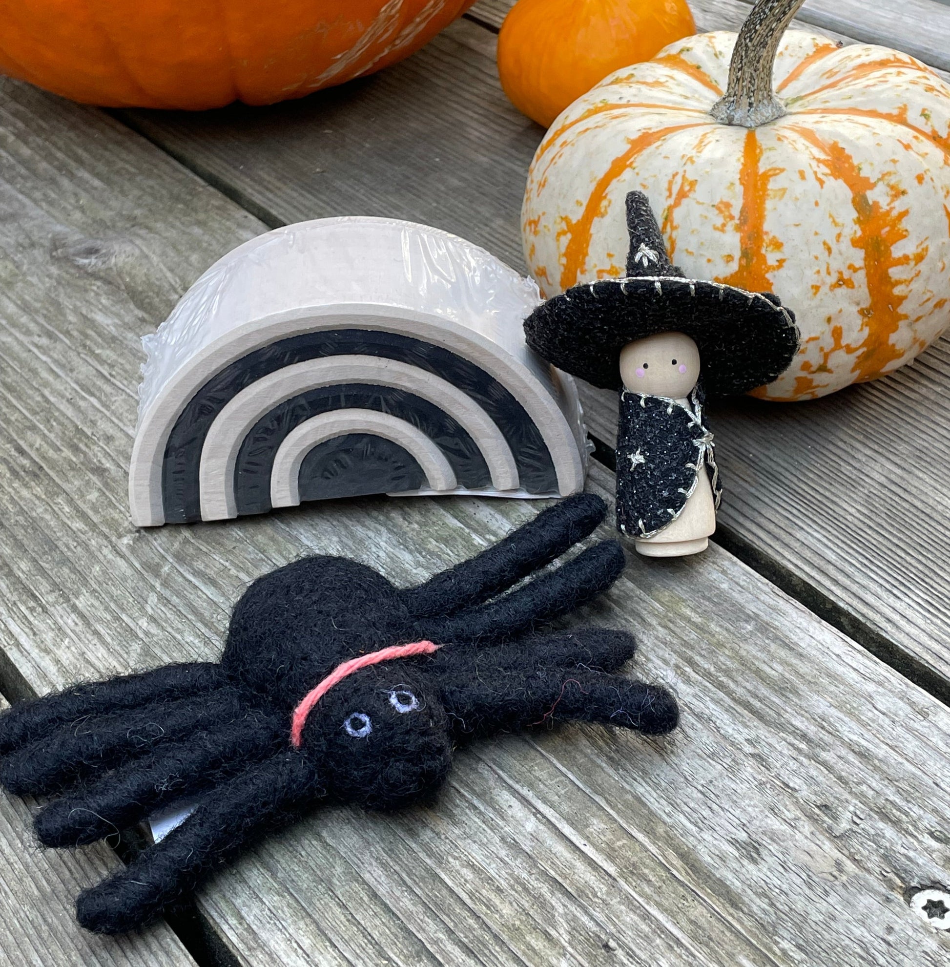 felt spider, witch peg doll, and small monochrome arch with pumpkins in the background