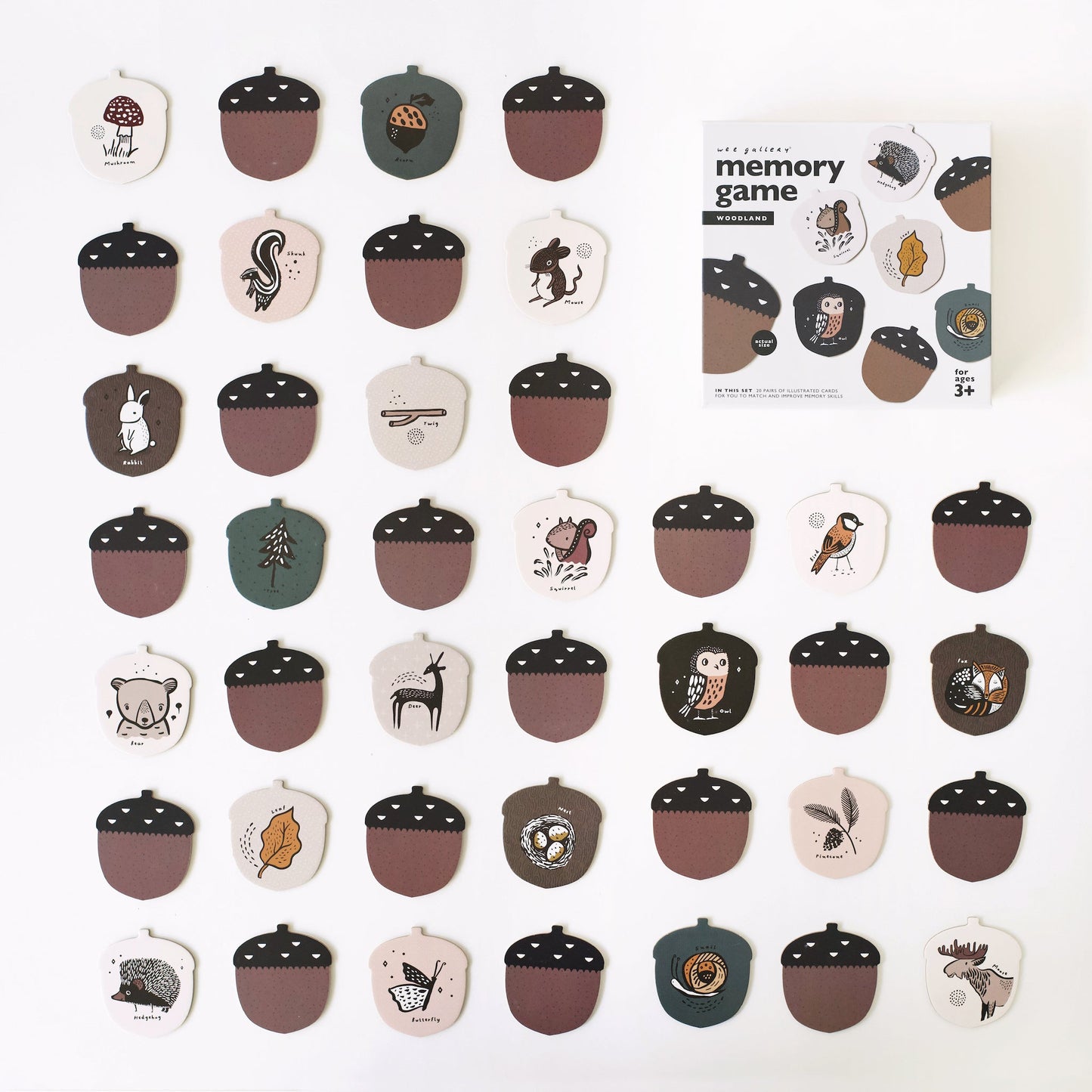 Acorn-shaped game pieces with illustrations on a white background, accompanied by a memory game packaging.