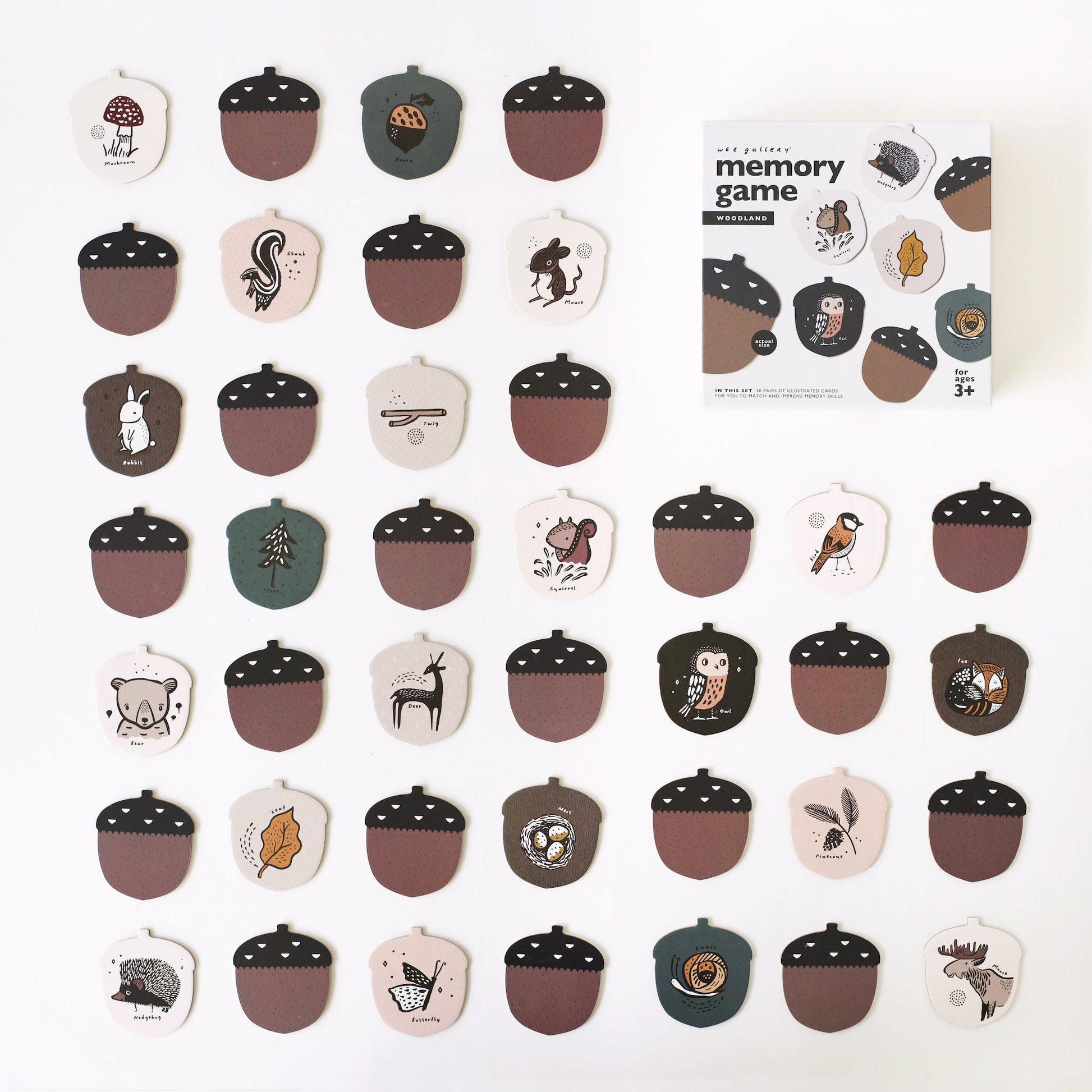Acorn-shaped game pieces with illustrations on a white background, accompanied by a memory game packaging.