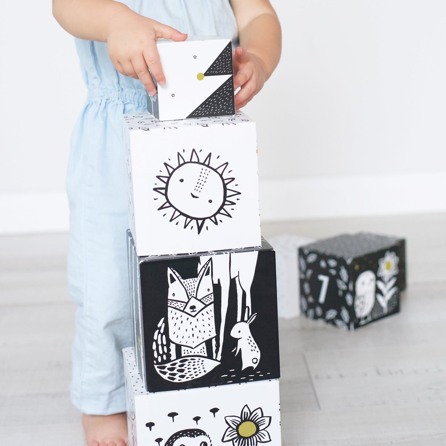 Child playing with black and white blocks featuring animal and nature designs on a light background.