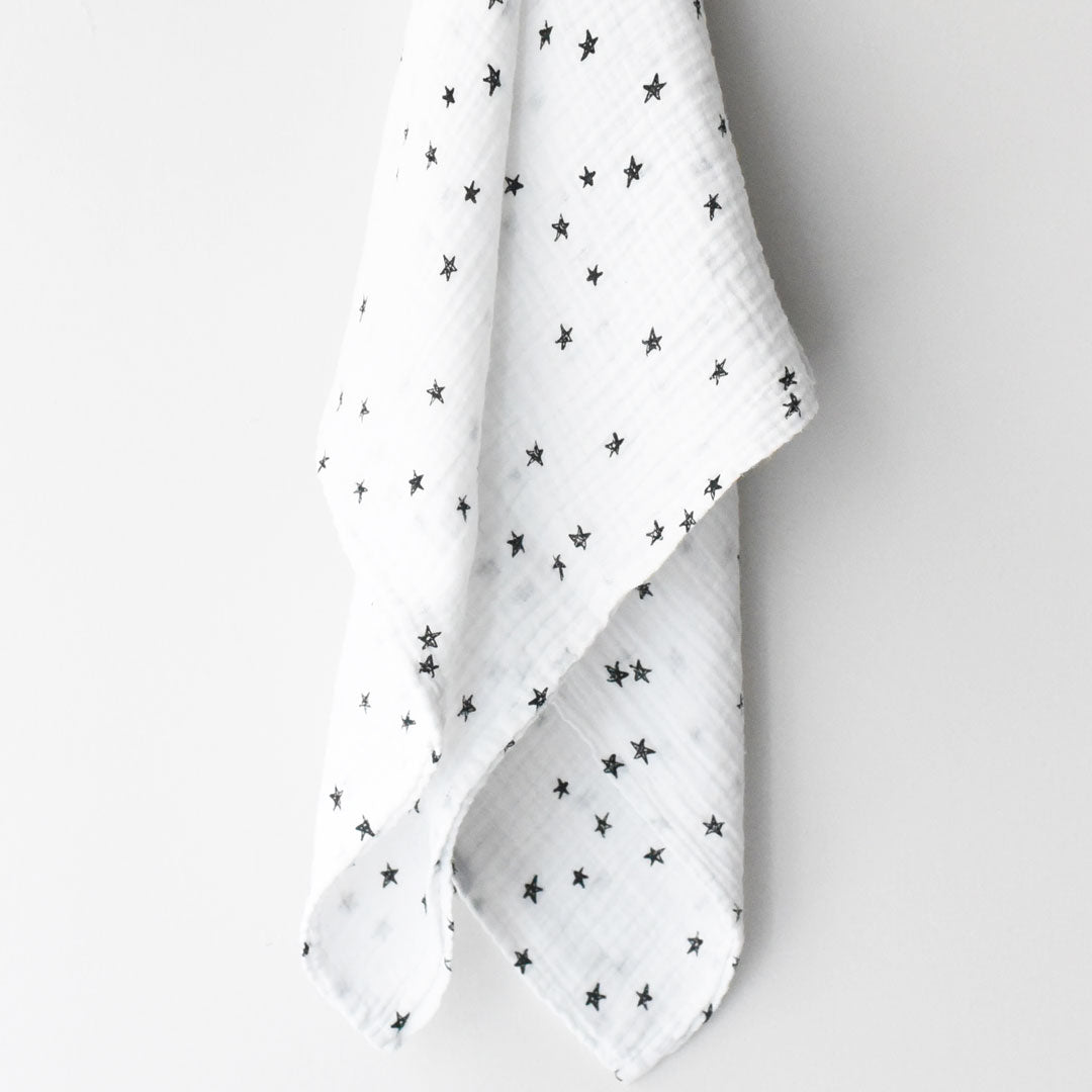 White fabric with black star pattern draped over a white surface