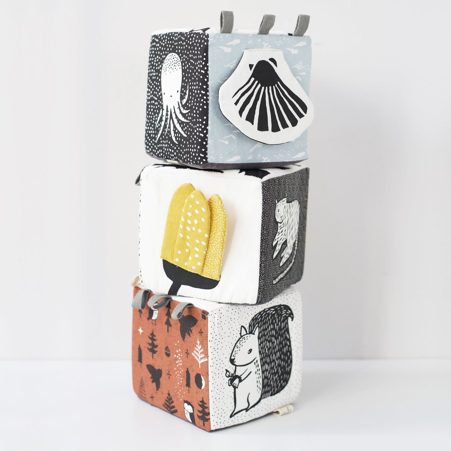 Stack of three patterned blocks with illustrations on a white background