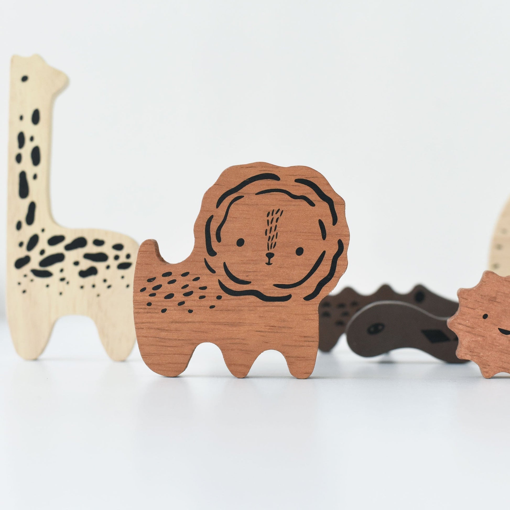 Wooden toy animals including a giraffe, lion, and hedgehog on a white background