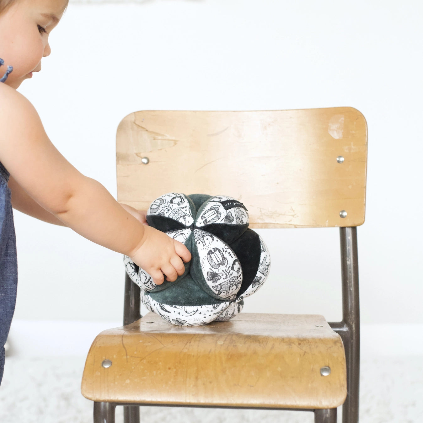 baby placing a clutch ball on a chair