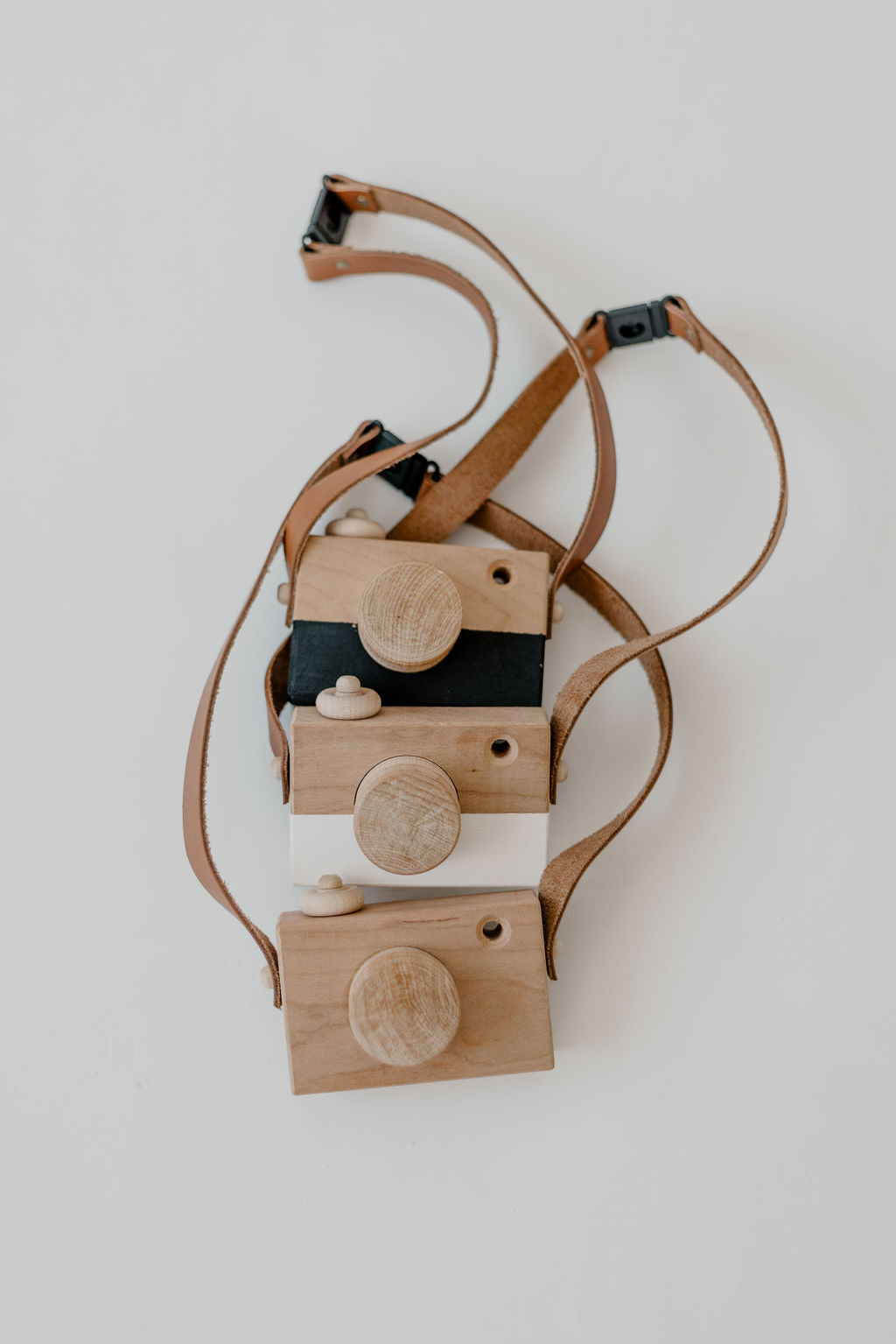 Wooden toy camera with a strap on a light gray background