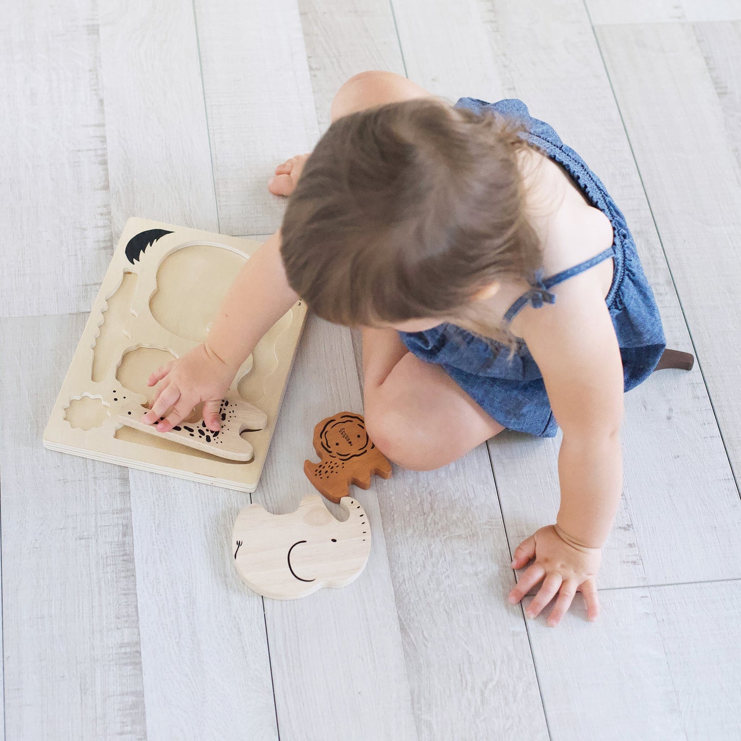 Child playing with wooden toys on a light wooden floor